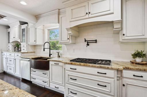 Wolf cooktop with downdraft vent, and large farmhouse sink.