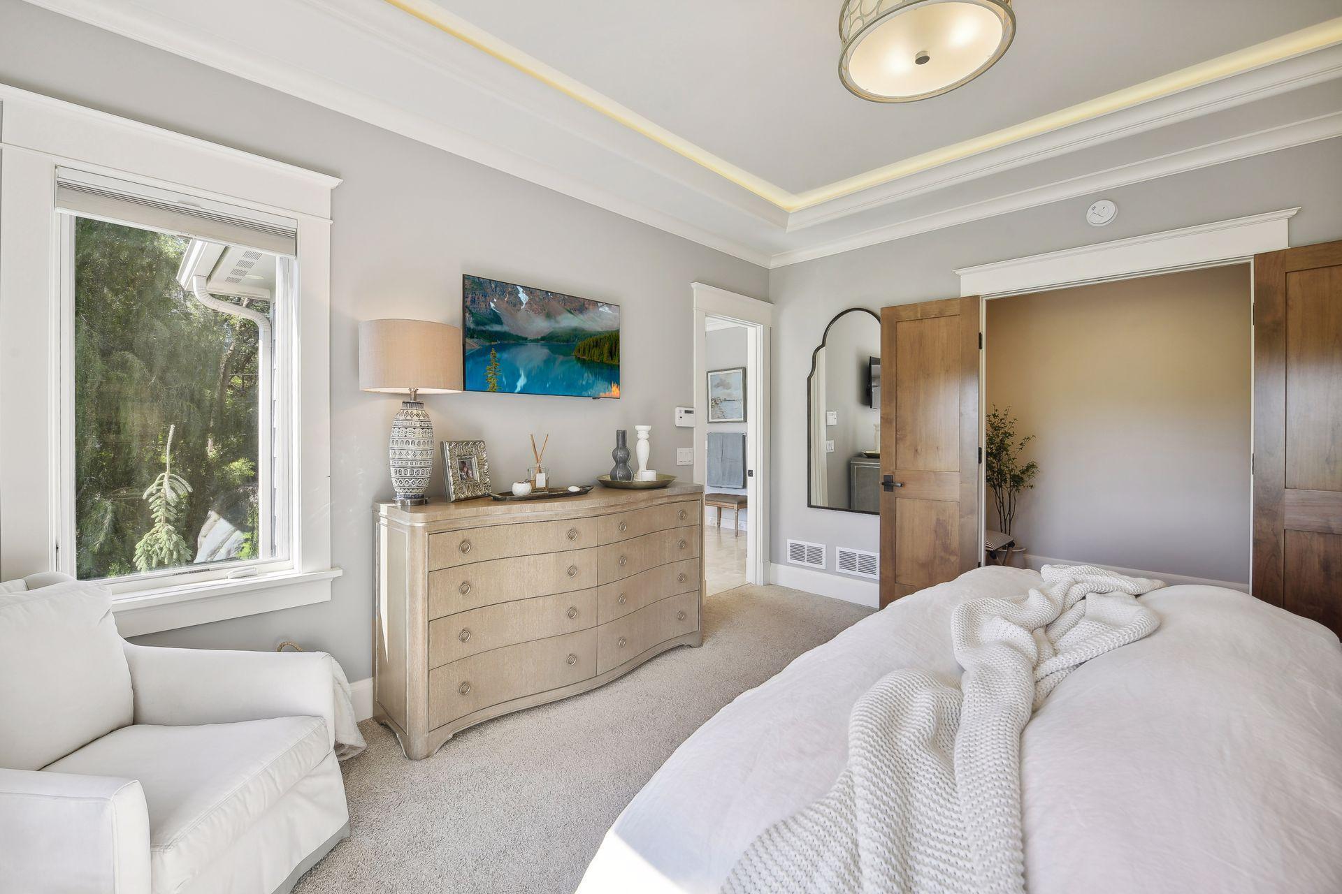 Main floor primary with multi-layered crown trim with soffit lighting, in-ceiling speaker in bedroom and bathroom.