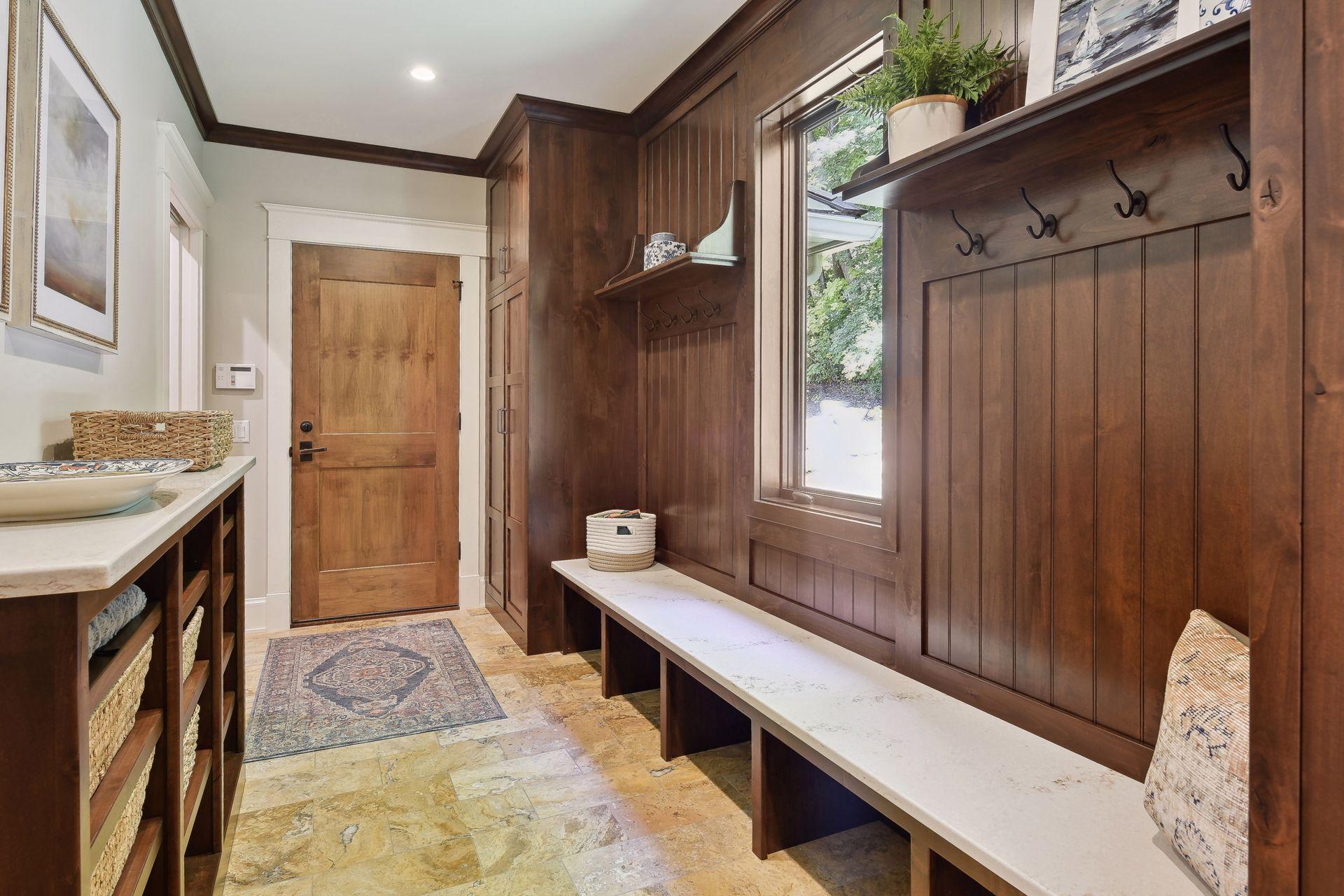 Mudroom with floor to ceiling cabinets, built-in Hanstone bench and counter top. Natural stone flooring