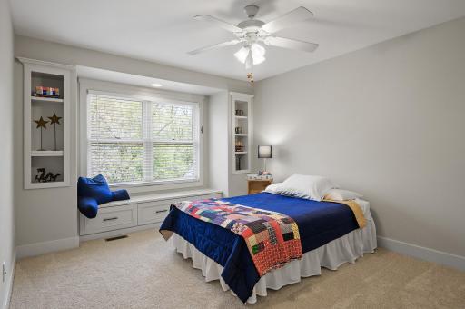 View of bedroom #2 on the upper level - all with built-in storage, ceiling fans, and charming window seats