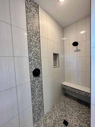 Doorless walk-in shower with bench. Floor to ceiling tile, water controls near entry so you can stay dry while the water warms up.