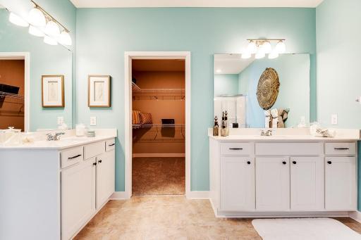 Fantastic primary en suite with separate vanities, quartz countertops and a large walk-in closet with wire shelving included. Staged model photos. See listing agent for home specific selections.