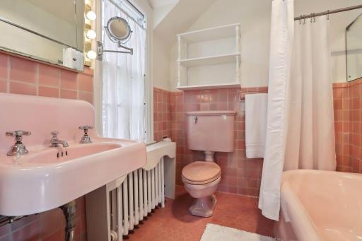 Primary suite full bath with original tile and cast iron tub.