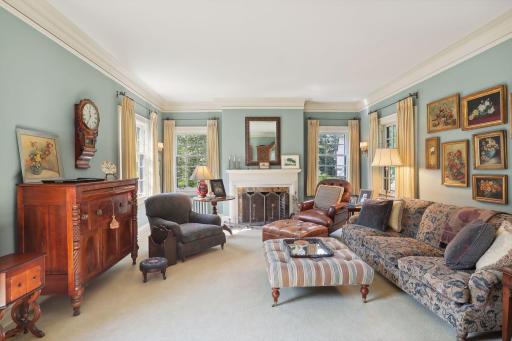 The living room features a corner of windows, enameled woodwork, a wood-burning fireplace, and views into the four season porch which overlooks the backyard. Lovely divided light sash windows open to the porch.