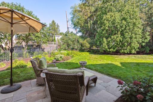 Pretty garden beds and matures trees surround the private backyard with wrought iron perimeter fencing.