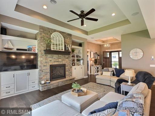 Gather in the living room offering trey ceiling, wood floor, custom built-ins and a gas burning radiant fireplace with stone accents.
