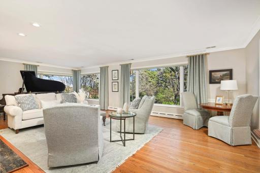 Picture windows showcase mature landscaping and glimpses of city lights