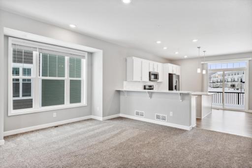 Open kitchen with a peninsula overlooking the family room and dining room. Photos are not of actual home. Actual home will be similar. Some colors and features may vary.