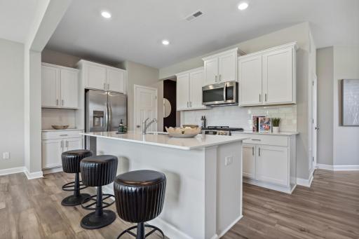 This spacious kitchen features a pantry, quartz kitchen countertops, under mount sink, recessed lighting, LVP flooring, ceramic tile backsplash, stainless appliances and more!