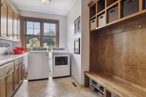 The mudroom and laundry room stand as paragons of convenience, with a coat closet, custom lockers, sink, washer, dryer, and built-in cabinets. From this space, the entrance to the three-car garage awaits, a seamless transition from indoor to outdoor