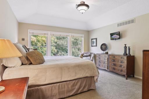 The primary suite is a retreat unto itself. The bedroom boasts a lofted ceiling that amplifies the sense of space.