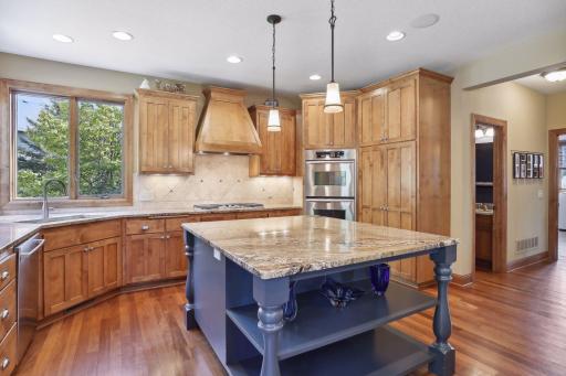 The sizable center island has been painted an elegant dark blue. The kitchen boasts alder cabinets, granite countertops, gas cooktop with a decorative hood, double oven, refrigerator and dishwasher.