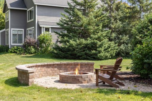 A paver patio and fire pit invite gatherings under the open sky.