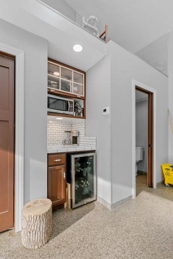 Service bar includes painted cabinetry, beverage refrigerator, subway tile countertops and backsplash