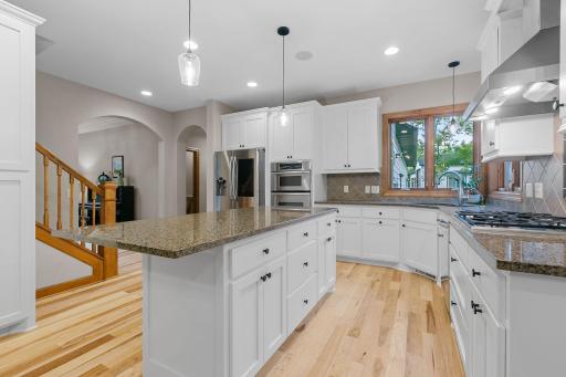 Custom cabinetry features enameled flat paneled doors, under cabinet accent lighting, full height pantry, roll-out storage, workstation w/ file drawers, 42"h uppers and "eat-in" center island