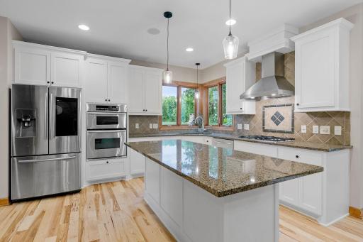 Stainless steel appliances include French door refrigerator, gas cooktop w/ decorative hood, dual wall ovens, dishwasher and microwave