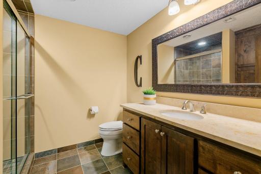 Rustic alder vanity w/ stone countertop, linen cabinet and ceramic tile flooring in the 3/4 Bathroom