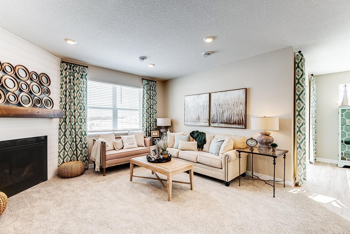 The homes tucked back living room with the corner gas fireplace makes for a cozy feeling home. Staged model photos. See listing agent for home specific selections.