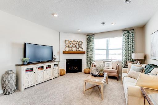 The homes tucked back living room with the corner gas fireplace makes for a cozy feeling home. Staged model photos. See listing agent for home specific selections.