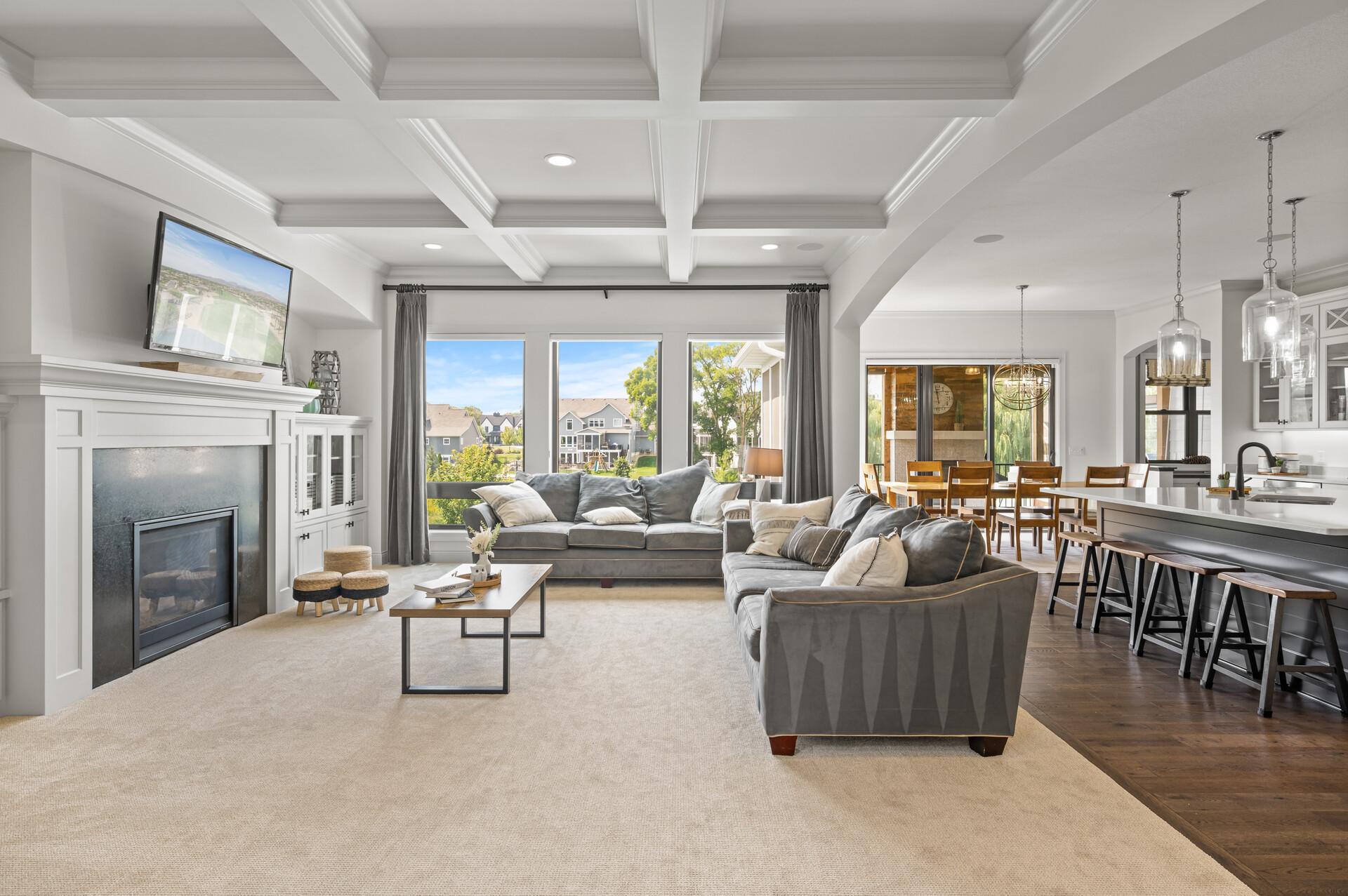 Gonyea built home with impeccable attention to detail and breathtaking architectural features throughout the home, showcasing the dedication to design and craftsmanship. Living room with a gas fireplace, elegant coffered ceiling and backyard views.