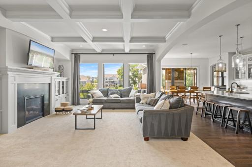 Gonyea built home with impeccable attention to detail and breathtaking architectural features throughout the home, showcasing the dedication to design and craftsmanship. Living room with a gas fireplace, elegant coffered ceiling and backyard views.