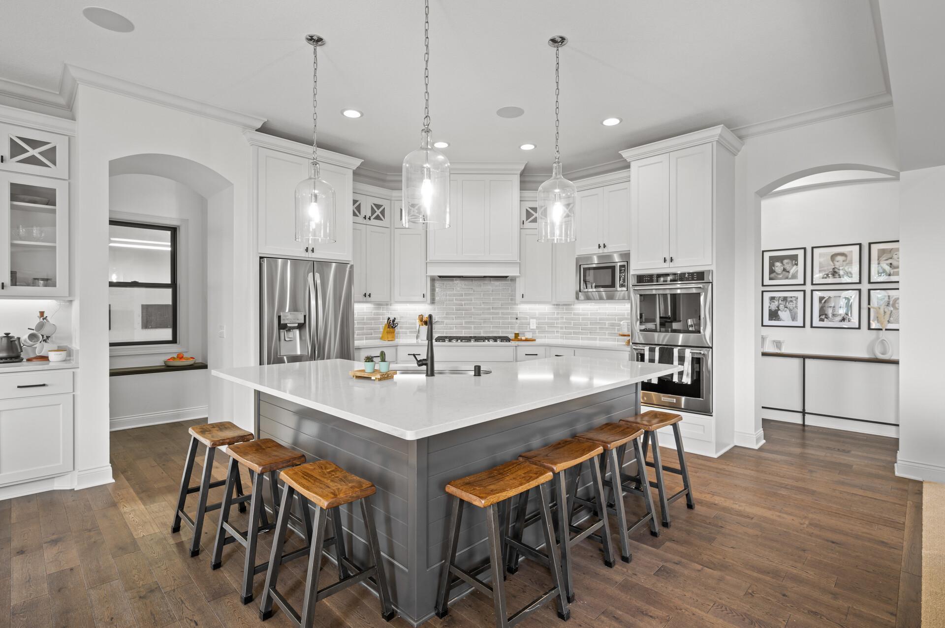 Exquisite kitchen featuring Quartz countertops, stylish tile backsplash, top-of-the-line appliances, and an oversized island for culinary preparation and casual dining.