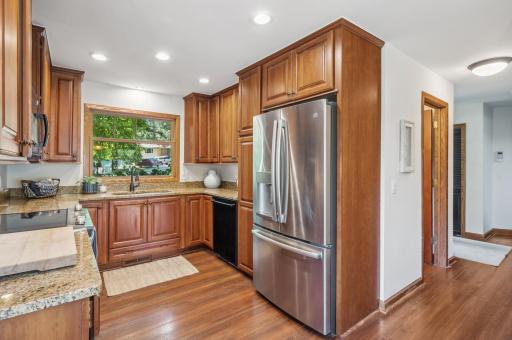 The updated kitchen boasts granite countertops, stainless steel appliances, and abundant storage, flowing seamlessly into a sunlit dining area.