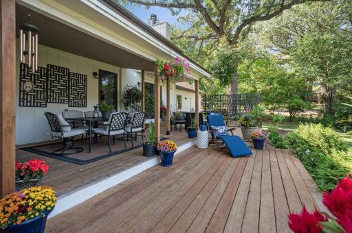 This backyard offers a generous expanse of open space, featuring a sizable deck perfect for outdoor gatherings. It also boasts a covered area for sheltered relaxation and enjoys picturesque views of a serene lake.