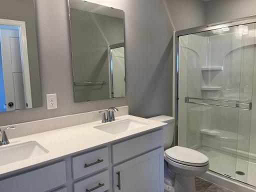 An extension of the owner's suite, this private and spacious bath contains a double-vanity and a large shower with a glass door.