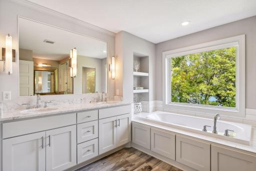 A spa-worthy Primary Bathroom - this space features heated tile floors, a comfort height vanity with marble countertops and a jetted bathtub.