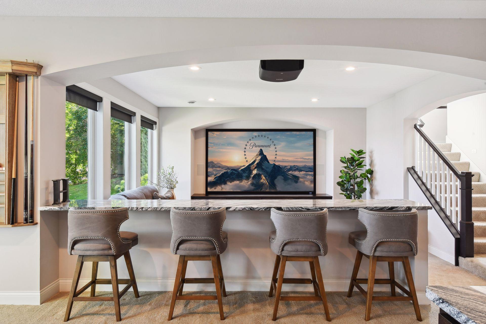 Perfect for cheering on your favorite sports teams or curling up for movie night, the lower level family room features a custom bar with granite countertops and a large projection screen.