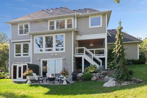 The home is surrounded with professional landscaping that features flowering shrubs, lush hostas and evergreen trees.