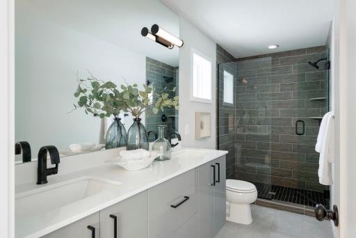 The owners bath is complete with 2cm bathroom vanity countertops, Moen undermount sinks and custom-built raised wall-mounted vanity cabinets with REHAU cabinet doors & drawers. The ceramic tiled shower and heavy glass door feels spa-like!
