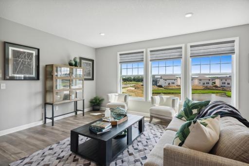 Big windows to the outside enlighten the living spaces. This particular home site is surrounded with beautiful mature trees. This picture is of a former model and not of actual home/home site.