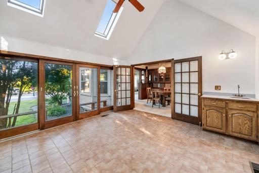 The sunroom is connected to the formal dining room and also has a bar sink in the corner.