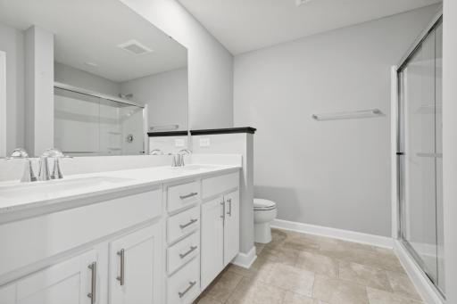 An extension of the owner's suite, this private and spacious bath contains a double-vanity, a private water closet, a large shower and a linen closet. (Photo of a completed home, actual home's finishes may vary slightly)
