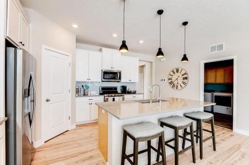 Open concept design includes Informal dining at the large kitchen island. Photo of model home to show with furniture