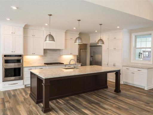 There is an awesome island in the kitchen with seating and elegant lighting.