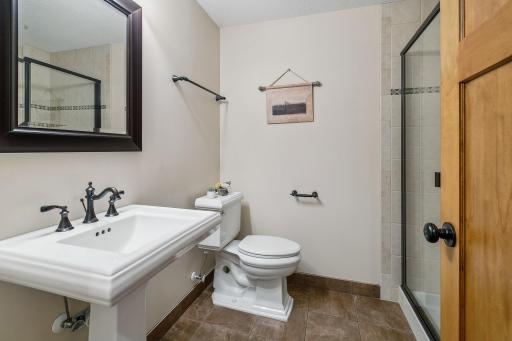 Lower level 3/4 bath with Kohler pedestal sink, toilet and glass shower door. Even a linen closet inside that bath.