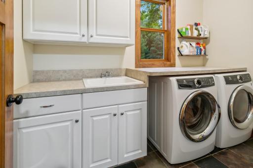 Main floor Laundry just off back hall features sink, storage cabinets and hanging space