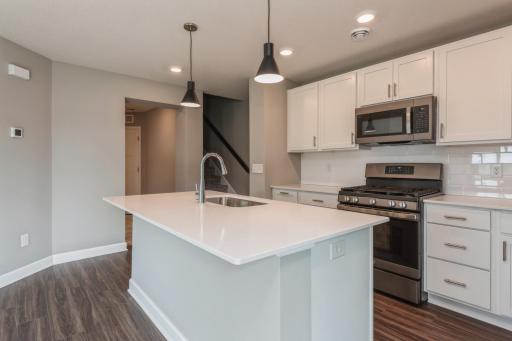 Equipped with gorgeous kitchen appliances, quartz countertops, a kitchen island and plank-style flooring throughout, this kitchen adds distinction & character to the home. *Photos are of another home, colors and finishes may vary.