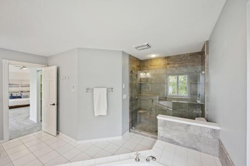 Shower has glass doors and tiled walls.