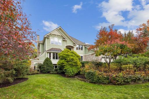 House has notable features, such as copper topped bay window, stone accents, exterior lighting, and beautiful gateways into garden areas.