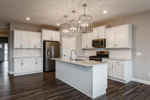 This spacious kitchen features a sizable pantry, quartz countertops, under mount sink, recessed lighting, LVP wood floors, stainless appliances and more!
