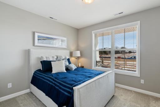 One of two generously sized secondary bedrooms with spacious closets. (Photo of decorated model, actual home's finishes may vary slightly)