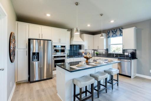 A stunning kitchen with ample counter space, double ovens, and a 7-foot island provides the perfect setting for entertaining guests.