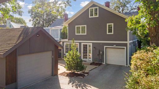 The newer detached garage, stone paver driveway leading to the attached garage, stone patio, and thoughtful landscaping create a charming and private outdoor space.