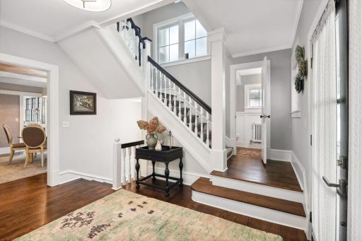 The gracious front entry hall. Beautifully crafted staircase. A powder room is located just off of the stair landing. Notice the gorgeous hardwood floors, crown moulding, and extensive custom mill work throughout the home.