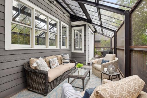 A wide screened porch with a plexiglass solarium roof that provides some protection from weather. Sash windows provide connectivity to the kitchen. Low maintenance decking.