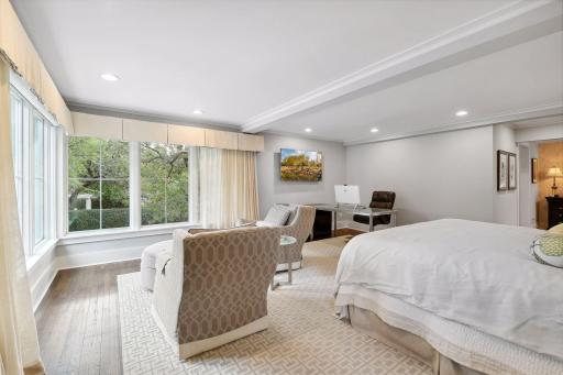The spacious primary bedroom accommodates a window sitting area. Pretty views of the mature trees, historic homes, and W Lake of the Isles Parkway.